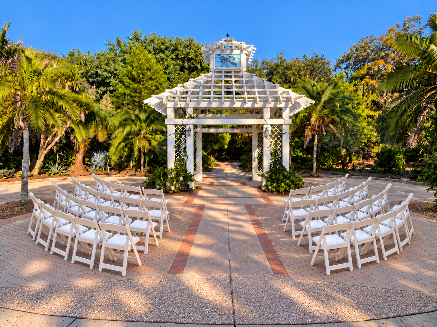 Photo of the East Gazebo wedding site. It features a white gazebo, green palm trees, and rows of white chairs.