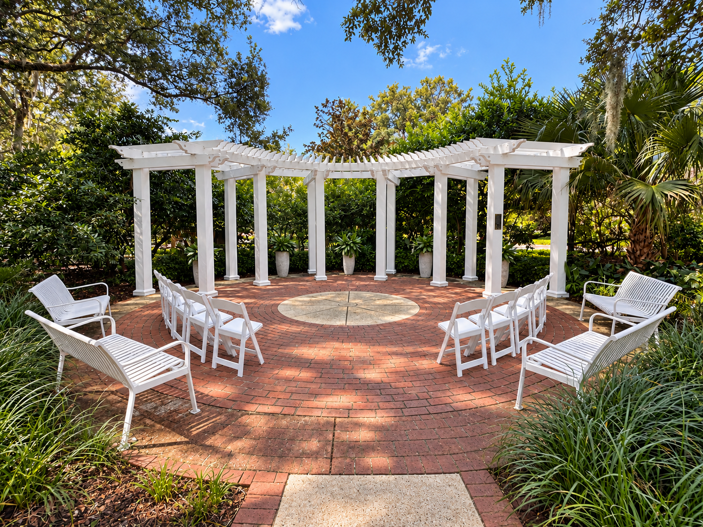 Photo of the South Trellis wedding site. It features a large white trellis, beige and red bricks, white benches, and white chairs.