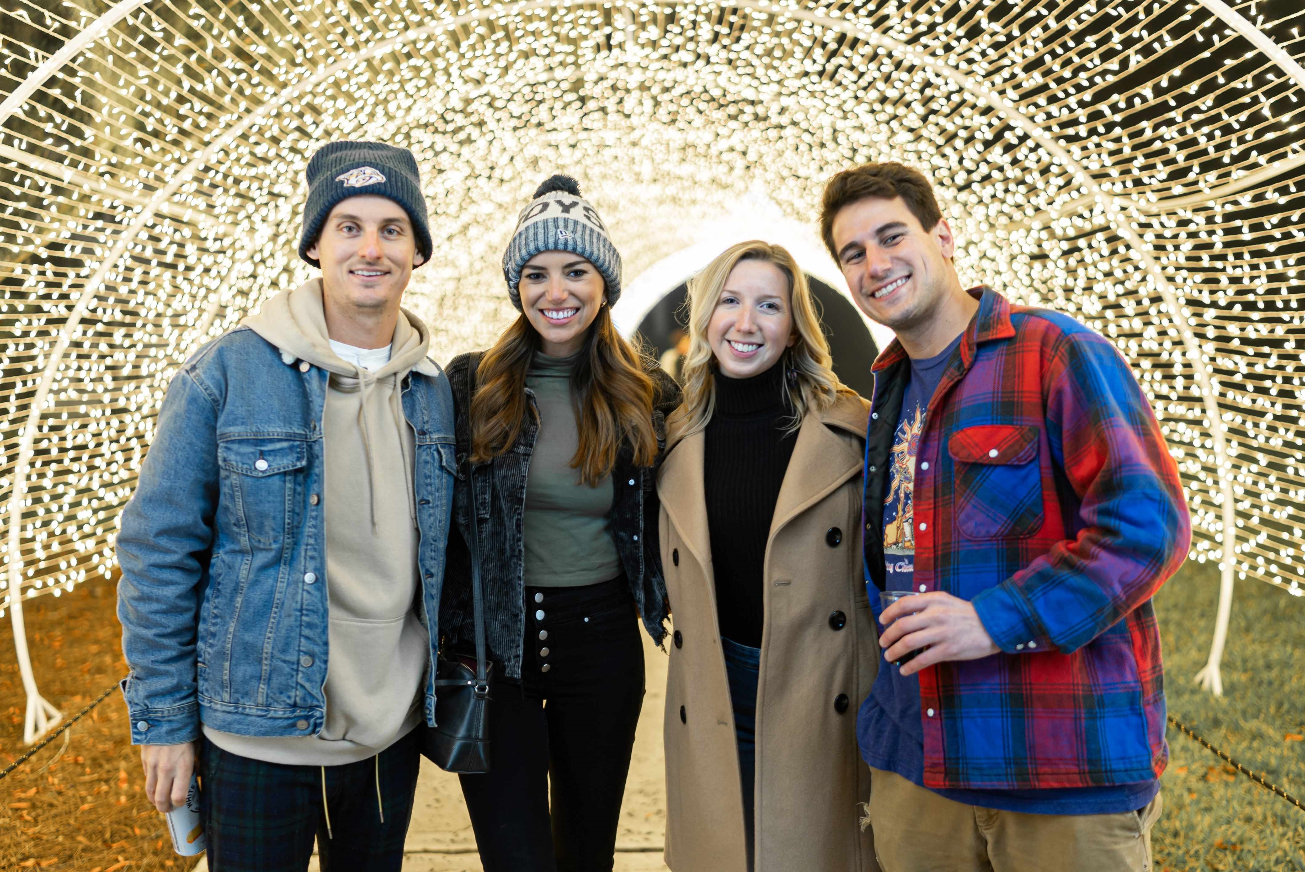 A group of friends in winter clothes standing in front of a light installation