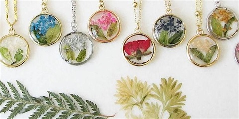 Jewelry pendants with botanical themes. They have dried flowers and leaves in them.