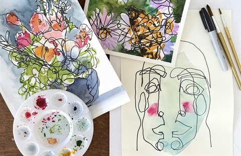 Watercolor paints next to paintings of flowers and people.
