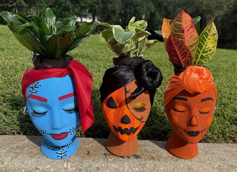 Mannequin head planters with green plants in them.