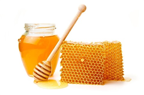 Jar of honey next to two pieces of honeycomb.