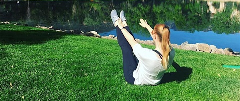 Person stretching in a pilates pose on grass.