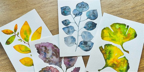 Paintings of leaves and flowers on watercolor paper. The paintings are yellow, blue, and purple.