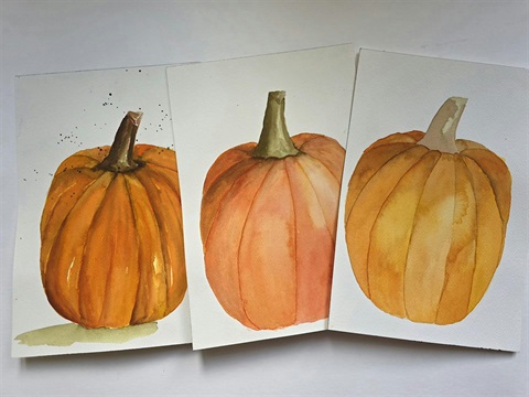 Watercolor painting of three orange pumpkins.