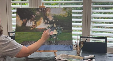 A person painting a flower bouquet on a canvas