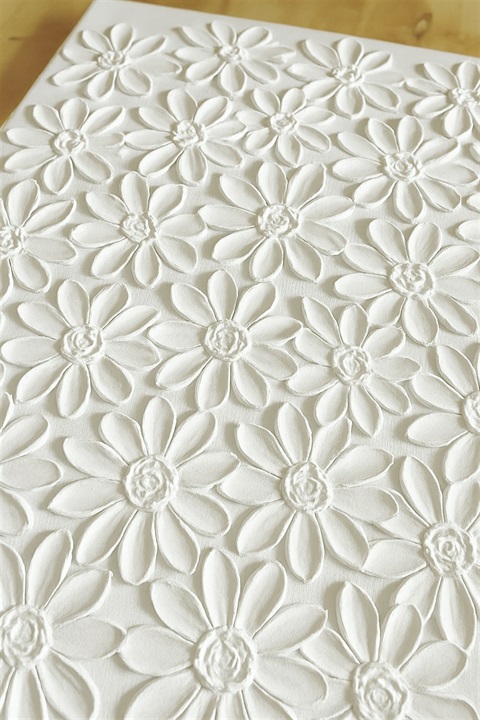 Textured painting. It is white with flower shapes.