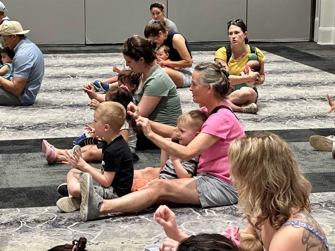 Children and parents sitting on a gray patterned carpet