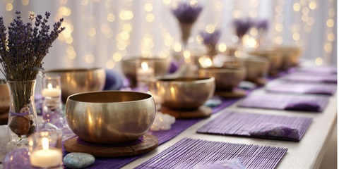 A table set with gold sound bowls and purple napkins